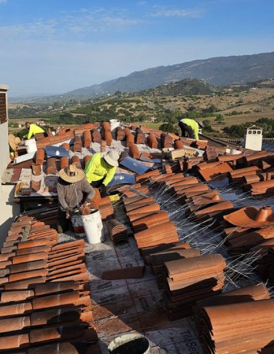 Skilled roofing contractor carefully replacing broken tiles during a tile roof repair project on a residential home