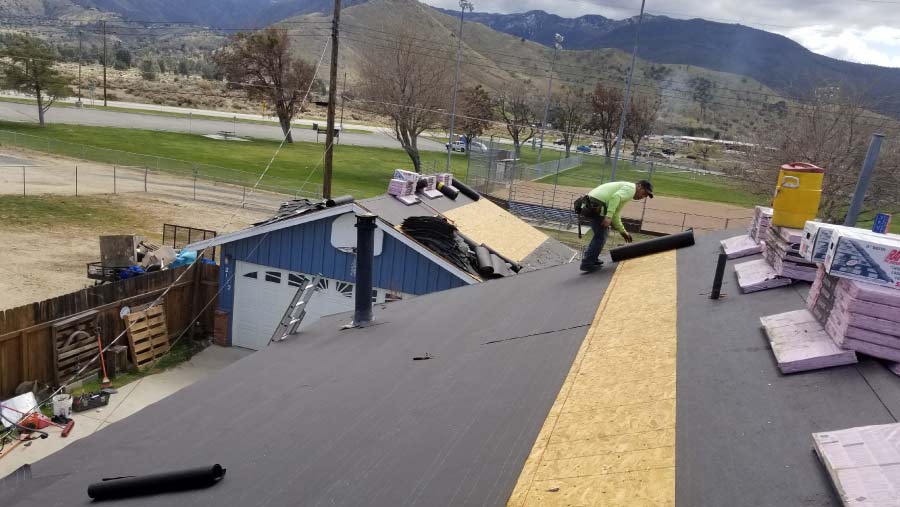 roll roofing Professional roofer repairing a roll roof by replacing damaged sections and applying protective coatings for durability