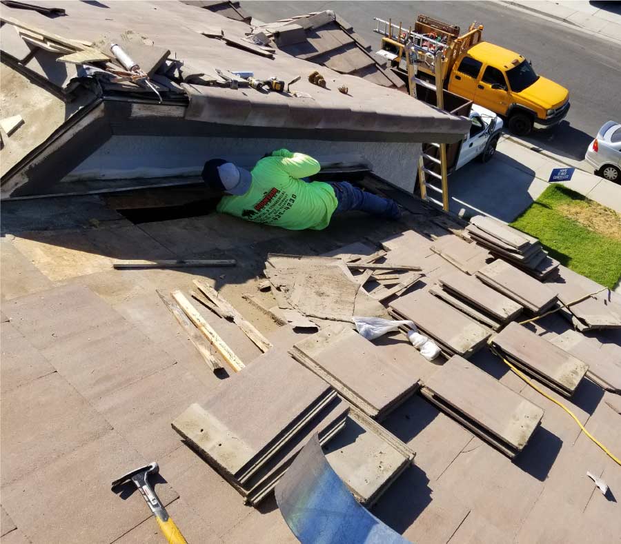 roof-repair-in-bakersfield roofer in a house in bakersfield doing roof repair of a tiles roof